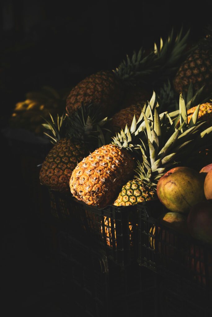 A close-up of ripe pineapples stacked in a basket under sunlight.